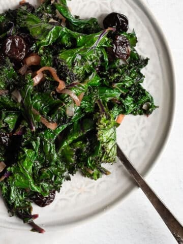 braised kale with cherries on a white plate