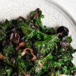 braised kale with cherries on a white plate