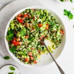 Cauliflower tabbouleh in a white bowl, garnished with mint, lemon and parsley