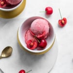 Two scoops of sweet cherry sorbet in a bowl garnished with sweet cherries