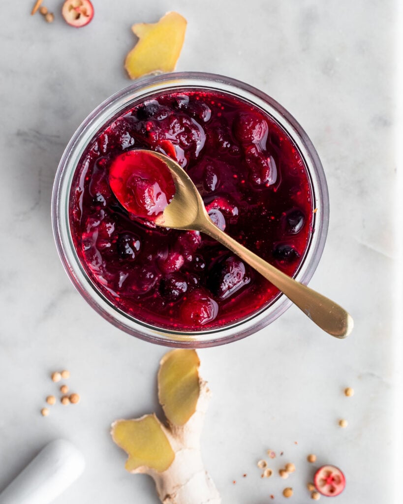 cranberry compote in a glass jar on a marble surface