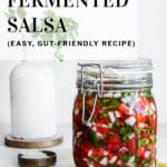 Fermented salsa in clip-top jar on white surface. Cilantro and lime in background.