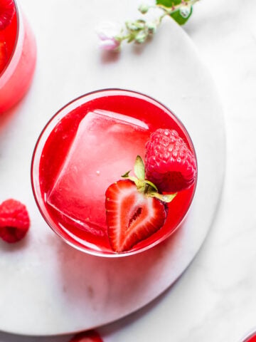 Three glasses of fruit kvass shot from overhead, garnished with ice and strawberries