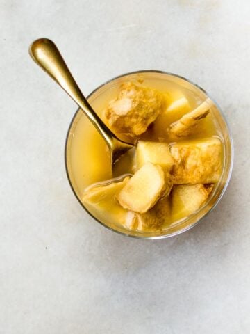 ginger bug in a short glass with a golden spoon on a marble surface