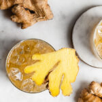 ginger kombucha in glasses of ice garnished with fresh ginger