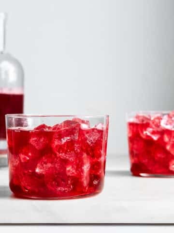 Hibiscus kombucha in glasses with ice and a bottle of hibiscus kombucha in the background