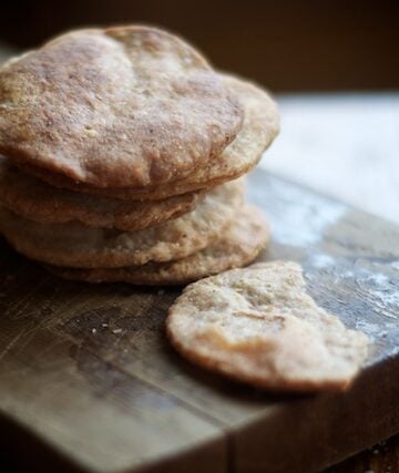 Stack of homemade round crackers on wooden cutting board