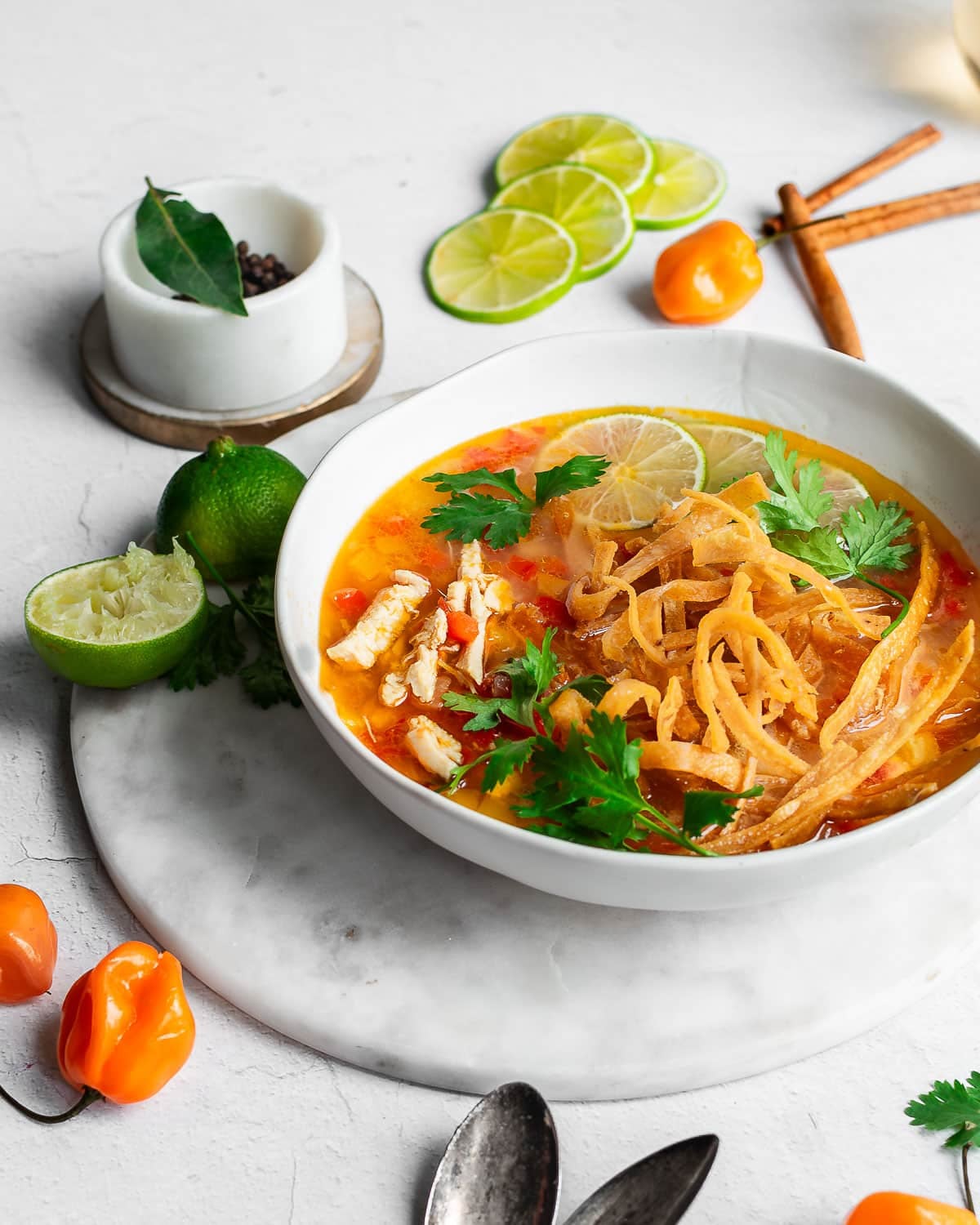 Lime soup in a bowl garnished with fresh limes, fried tortillas and cilantro