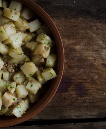 Roasted potatoes with liver in a terra cotta bowl on wooden background
