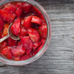 macerated strawberries in glass bowl on wooden surface