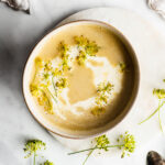 Potato dill soup shot from overhead, garnished with cream and dill flowers