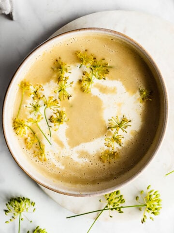 Potato dill soup shot from overhead, garnished with cream and dill flowers