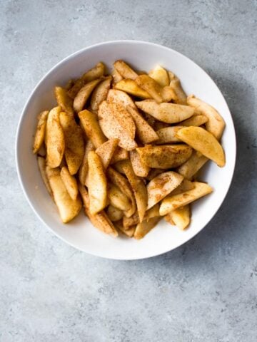 sauteed apples in a ceramic bowl on concrete
