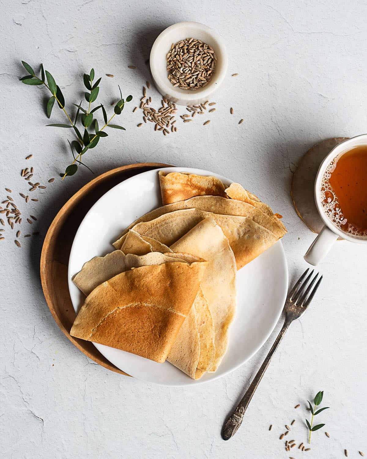Sourdough rye crepes on a white bplatewl, rye berries in the background