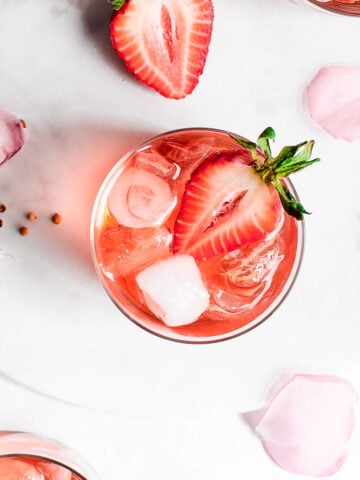 Strawberry smash in glass cup, garnished with ice and sliced strawberry