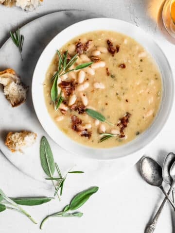 White bean soup garnished with pancetta, sage and rosemary